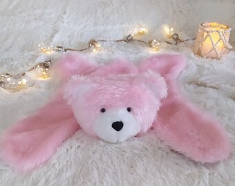 May include: A plush pink teddy bear security blanket featuring a soft, fuzzy pink bear head with a white muzzle and a black nose, attached to a flat, matching pink faux fur blanket body with four extended limbs in a spread-out, flat position.