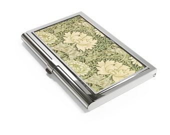 May include: A rectangular metal business card case with a polished silver finish. The top surface features a decorative inlay with a repeating pattern of cream-colored flowers and green foliage on a dark green background.