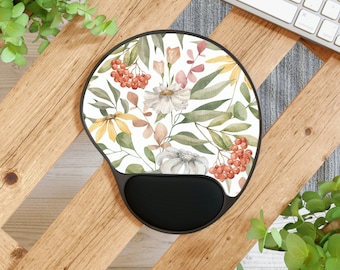 May include: A round mouse mat with a floral design featuring white flowers, green leaves, and red berries. The mouse mat has a black wrist rest.