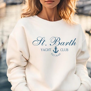 May include: White sweatshirt with a navy blue logo that says "St. Barth Yacht Club Est. 1648" with an anchor symbol.