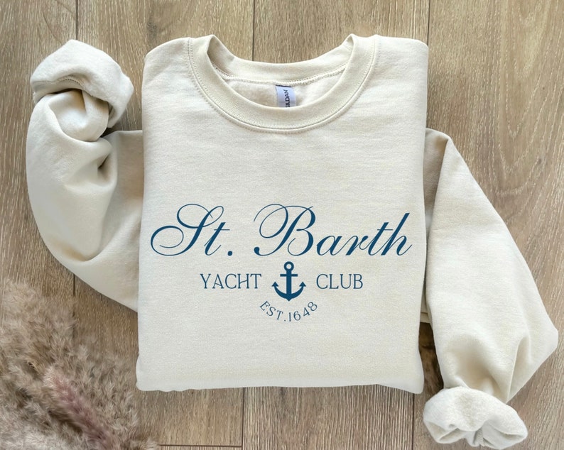 May include: A beige sweatshirt with a navy blue graphic that says "St. Barth Yacht Club Est. 1648" with an anchor symbol.