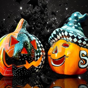 Könnte beinhalten: Zwei Halloween-Kürbisse aus Keramik. Einer ist orange und schwarz mit einem geschnitzten Gesicht. Der andere ist orange mit einem lächelnden Gesicht und einem Hexenhut. Der Hintergrund ist schwarz mit Sternen.