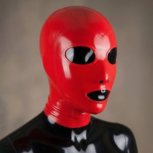 May include: A red latex hood with large oval eye openings and a small nose. The mouth is open, revealing a black interior. The hood is worn over a black garment.