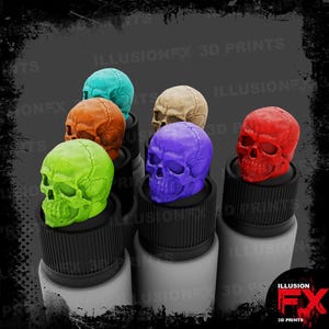 May include: A collection of six miniature human skull toppers in bright lime green, orange, teal, beige, purple, and red, each mounted on a black ribbed cap atop a white cylindrical bottle, with the text ILLUSIONFX 3D PRINTS visible in the background.