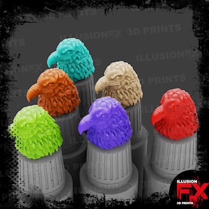 Puede incluir: Seis figuras de cabezas de águila en colores brillantes que incluyen verde azulado, naranja, verde lima, morado, beige y rojo. Cada cabeza de águila está montada sobre una base cilíndrica gris y estriada. El texto ILLUSIONFX 3D PRINTS es visible al fondo.
