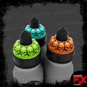 May include: Three bottle caps featuring a ring of miniature skulls in bright green, teal, and copper colors. Each cap has a black cylindrical top and a black base. The text ILLUSIONFX 3D PRINTS is visible on the caps and the background.