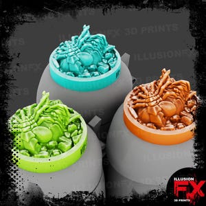 Puede incluir: Tres figuras circulares impresas en 3D con criaturas detalladas parecidas a arácnidos sobre bases texturizadas. Una figura es verde claro, otra es azul verdoso y otra es naranja. Cada una se asienta sobre un pedestal gris, liso y redondeado.