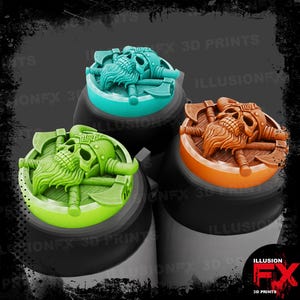 Puede incluir: Tres fichas circulares con un relieve de una calavera barbuda con casco de cuernos, colocada sobre hachas cruzadas. Las fichas son de color verde azulado, verde lima y naranja, cada una sobre una base cilíndrica negra con el texto ILLUSIONFX 3D PRINTS.