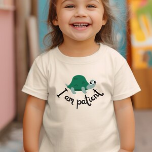 May include: A white t-shirt with a green turtle graphic and the text "I am patient".