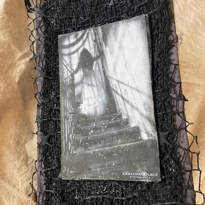 May include: A black and white photograph of a ghostly figure on a staircase, set within a black mesh frame. The photograph is labeled "Kristina Lacz photography". The overall theme is gothic and spooky.