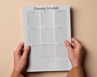 May include: A gray and white cleaning schedule planner with sections for each day of the week, daily, and monthly tasks. The title "Cleaning Schedule" is at the top. The planner is held by two hands.