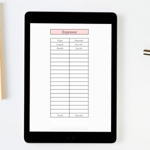 K&ouml;nnte beinhalten: Ein schwarzes Tablet zeigt einen Ausgaben-Tracker mit einer rosa &Uuml;berschrift "Expenses". Die Tabelle listet "Lunch" mit 11,00 $ und "Snack" mit 4,00 $ auf, insgesamt 15,00 $. Das Tablet liegt auf einer wei&szlig;en Oberfl&auml;che.