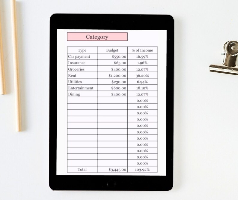 K&ouml;nnte beinhalten: Ein schwarzes Tablet zeigt eine Budget-Tabelle mit Kategorien wie Autozahlung, Lebensmittel und Miete. Die Tabelle zeigt Budgetbetr&auml;ge und Einkommensprozents&auml;tze. Eine Metallklammer und Holzst&auml;be befinden sich im Hintergrund.
