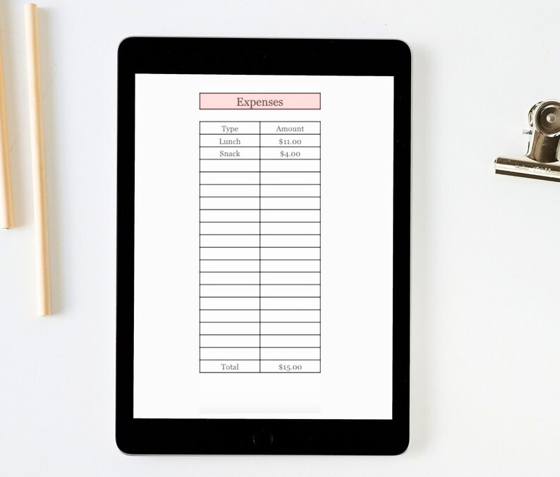 Puede incluir: Una tableta negra muestra un rastreador de gastos con un encabezado rosa que dice "Gastos". La tabla enumera "Almuerzo" a 11,00 &euro; y "Merienda" a 4,00 &euro;, con un total de 15,00 &euro;. Tambi&eacute;n se ven dos l&aacute;pices y un clip plateado.