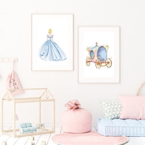 May include: Two framed prints, one with a watercolor illustration of Cinderella in a blue ball gown, the other with a pink and gold carriage.