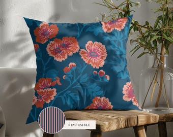 May include: A square throw pillow featuring a dark blue background with a repeating pattern of coral and pink flowers and leaves. A circular inset shows the reverse side of the pillow, which has a pattern of thin vertical dark blue and pink stripes.