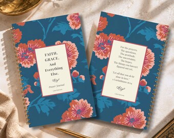 May include: Two spiral-bound prayer journals with a dark blue background featuring a coral and pink floral pattern. The left journal cover reads: FAITH. GRACE. And Everything Else. Prayer Journal Lisa Kanova. The right cover features a prayer text.