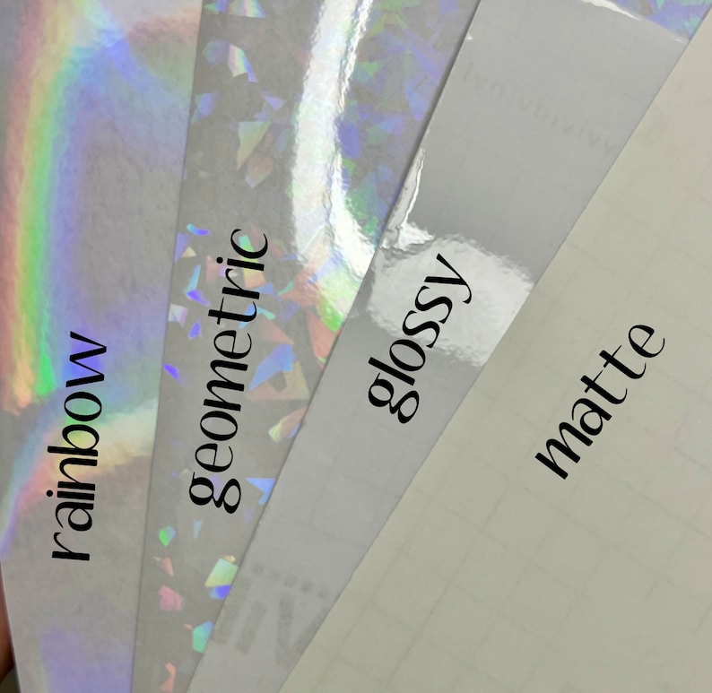 May include: Four samples of vinyl adhesive paper with different finishes: rainbow iridescent, geometric iridescent, glossy, and matte. The text labels are "rainbow", "geometric", "glossy", and "matte".