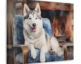 May include: A white and grey husky dog sits in a blue armchair in front of a fireplace. The dog is smiling and has its paws resting on the armrests. The fireplace is lit and has flames visible.