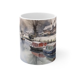 May include: A white ceramic mug featuring a winter scene of a canal with boats and houses covered in snow. The scene is painted in a watercolour style.