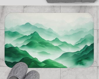 May include: A green and white bath mat with a watercolor-style design of mountains and fog. The mat has a soft, absorbent surface and is perfect for adding a touch of nature to your bathroom.