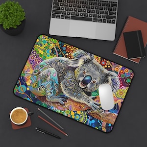 May include: A colorful mousepad featuring a koala bear with a detailed, abstract design. The koala is sitting on a branch with a colorful background of dots and swirls.
