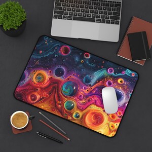 Puede incluir: Una alfombrilla de ratón abstracta colorida con patrones de remolino de rojo, naranja, amarillo, azul y morado. La alfombrilla de ratón tiene un borde negro y un ratón de ordenador blanco en la parte superior.