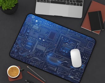 May include: A blue and white circuit board design mouse pad with a white computer mouse on top of it. The mouse pad is on a dark gray surface with a laptop, a cup of coffee, and pencils.