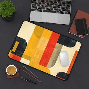 May include: A colorful geometric design mousepad with a white computer mouse on top. The mousepad has a cream background with yellow, red, orange, and black geometric shapes.