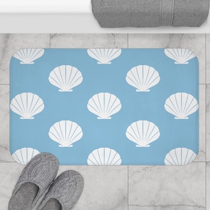 Alfombrilla de baño con forma de concha marina: alfombrilla antideslizante con un estampado minimalista de conchas en un suave estilo costero azul y blanco.