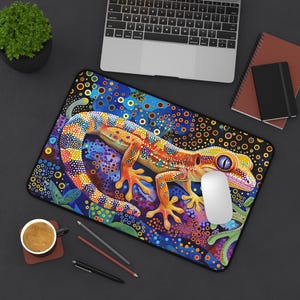 May include: A colourful mouse mat featuring a detailed illustration of a gecko with orange, yellow, and blue scales on a dark blue background with colourful dots and swirls.