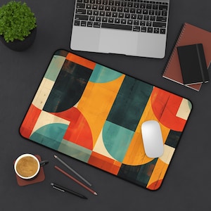May include: A colorful geometric design mousepad with a white mouse on top. The mousepad has a mix of yellow, blue, red, and green colors.