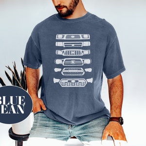 May include: A man wearing a blue jean t-shirt with a white graphic of a series of different car grilles. The grilles are stacked vertically on the shirt.
