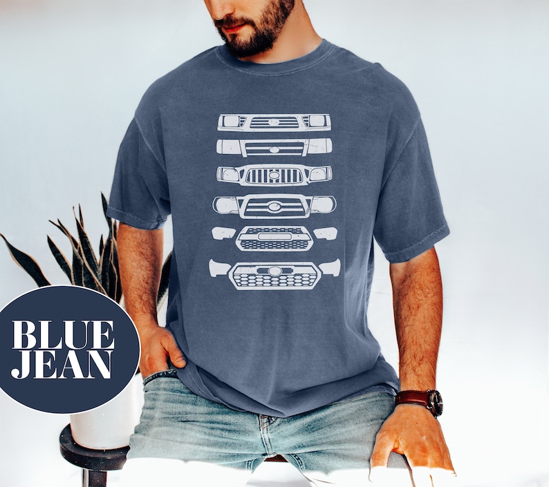 May include: A man wearing a blue jean t-shirt with a white graphic of a series of different car grilles. The grilles are stacked vertically on the shirt.