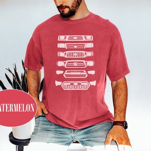 May include: A red t-shirt with a white graphic of a lineup of different Toyota Tacoma front grilles.