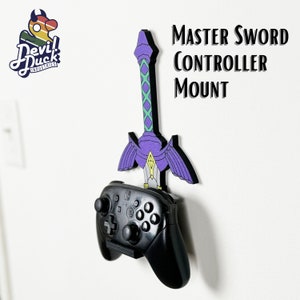 Puede incluir: Un soporte para mando en forma de Espada Maestra, de color morado y verde. El soporte tiene la forma de la Espada Maestra de la serie de videojuegos The Legend of Zelda. Un mando Nintendo Switch negro está montado en la espada.