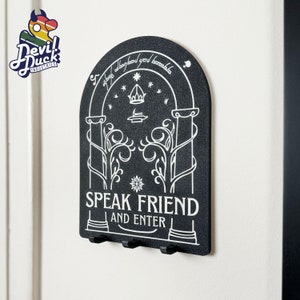 May include: Black key holder with a white design of a door with the text "Speak Friend and Enter".