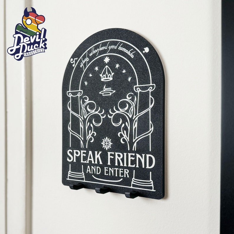 May include: Black key holder with a white design of a door with the text "Speak Friend and Enter".