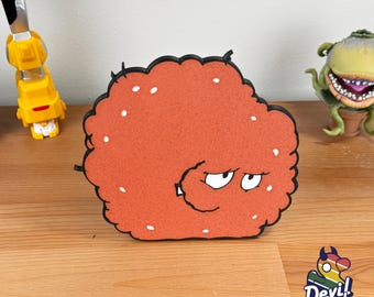 May include: A 3D printed red and white cartoon character with a grumpy expression. The character is shaped like a large, fluffy ball of hair. The character is made by Devil Duck Industries.