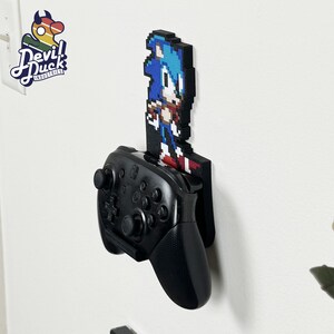 May include: A black Nintendo Switch controller mounted on a wall with a pixelated Sonic the Hedgehog character graphic.