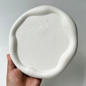 Op de afbeelding: Ronde witte dienblad met een golvende rand en een glinsterend oppervlak.