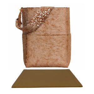 以下が含まれることがあります： フラップ留めと長いストラップが付いた茶色のスエード製ハンドバッグ。バッグは茶色の表面の上に置かれています。