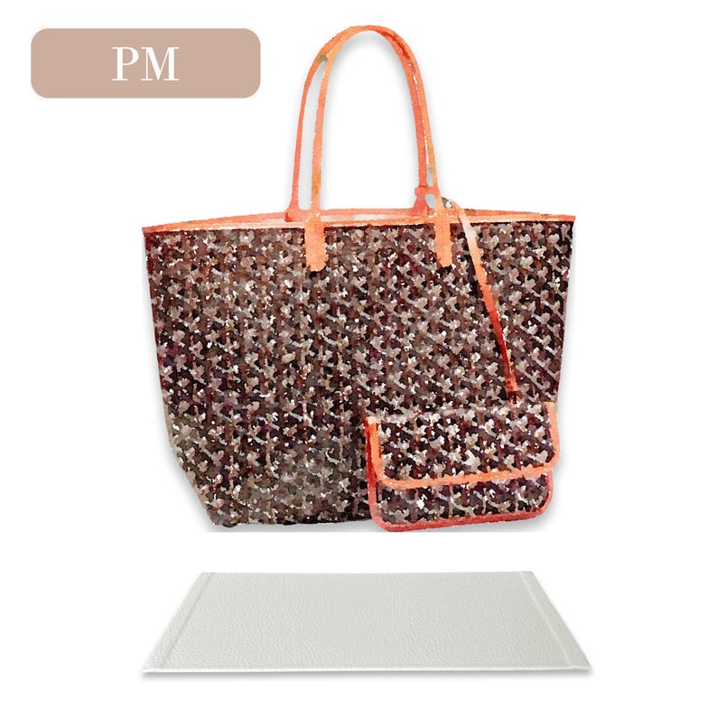 May include: A brown and black tote bag with orange handles and a matching smaller pouch. The bag has a pattern of small, repeated shapes. The bag is sitting on a white surface.