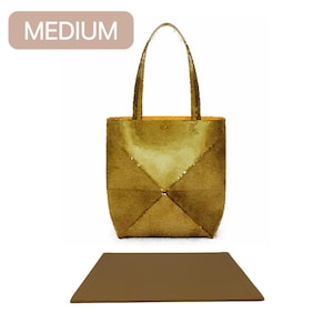 May include: A medium-sized, gold-coloured tote bag with a brown leather-like texture. The bag has a simple design with a single compartment and two top handles.