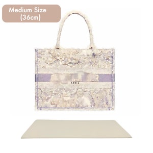 May include: A white and light blue tote bag with a floral pattern and the word "DIOR" printed on the front. The bag has a light blue strap and is 36 inches in size.