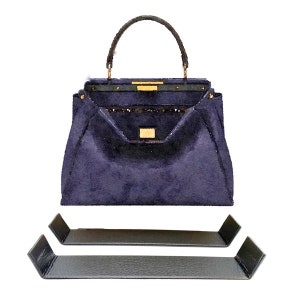 May include: A dark blue handbag with a gold clasp and a pair of black handbag stands.