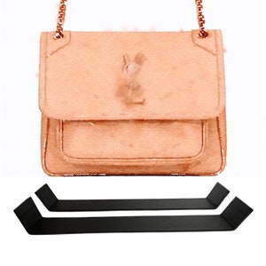 Puede incluir: Ilustración en acuarela de un bolso de color melocotón con una cadena dorada. El bolso tiene un cierre de solapa y un logotipo en la parte delantera. Debajo del bolso hay dos elementos decorativos negros y angulares.