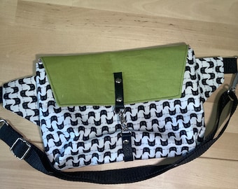 May include: A black and white patterned fanny pack with a green flap and a black adjustable strap.
