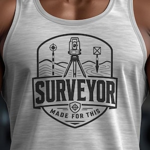 May include: A light gray tank top featuring a black graphic print of a surveying instrument on a tripod, a range pole, and a prism pole. The text reads SURVEYOR and MADE FOR THIS, enclosed within a shield-shaped emblem design on the chest.