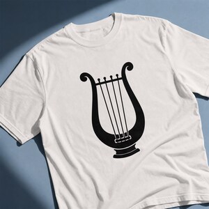 以下が含まれることがあります： 中央に黒い竪琴のグラフィックプリントが施された白い半袖Tシャツ。楽器のデザインは、U字型のフレームに4本の垂直な弦と湾曲した上端が特徴で、衣服の前面にはっきりと配置されています。